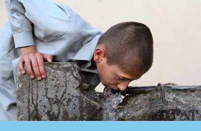 Photo of Afghan boy drinking from water fountain